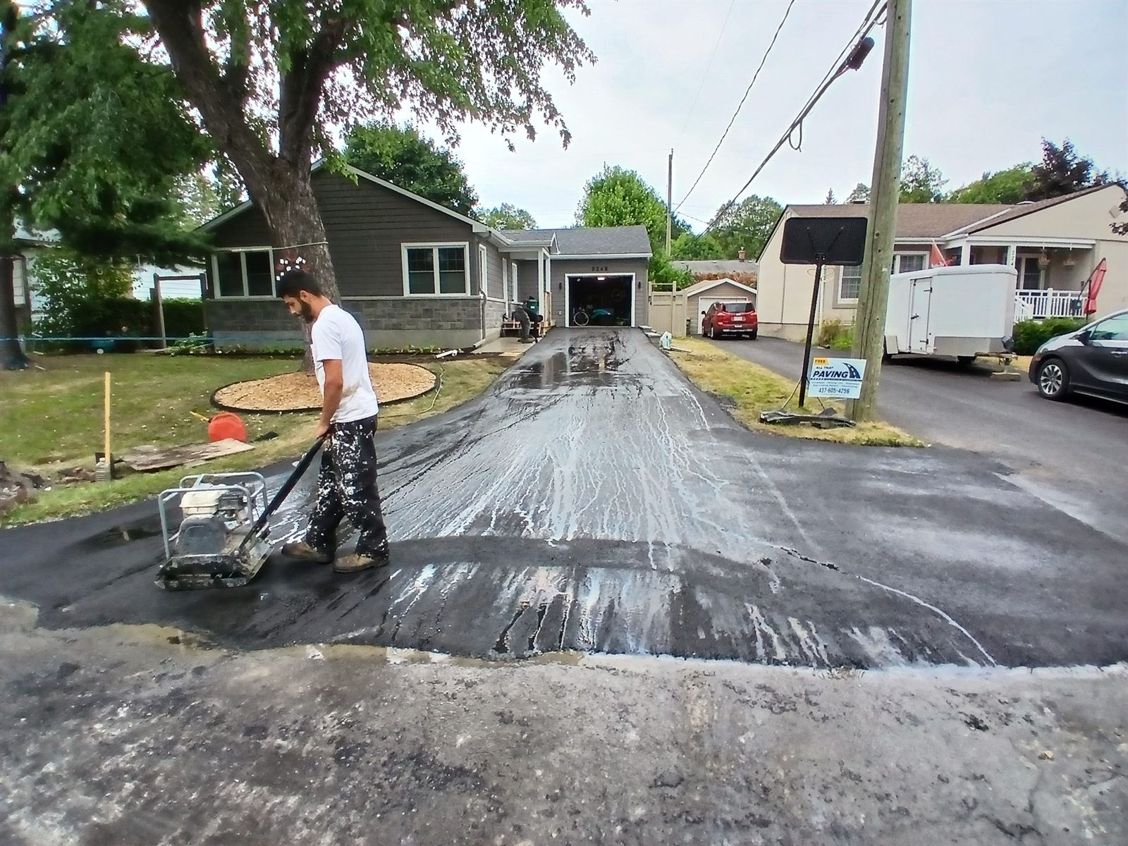 Worker applying sealcoat to a residential asphalt driveway in Ottawa