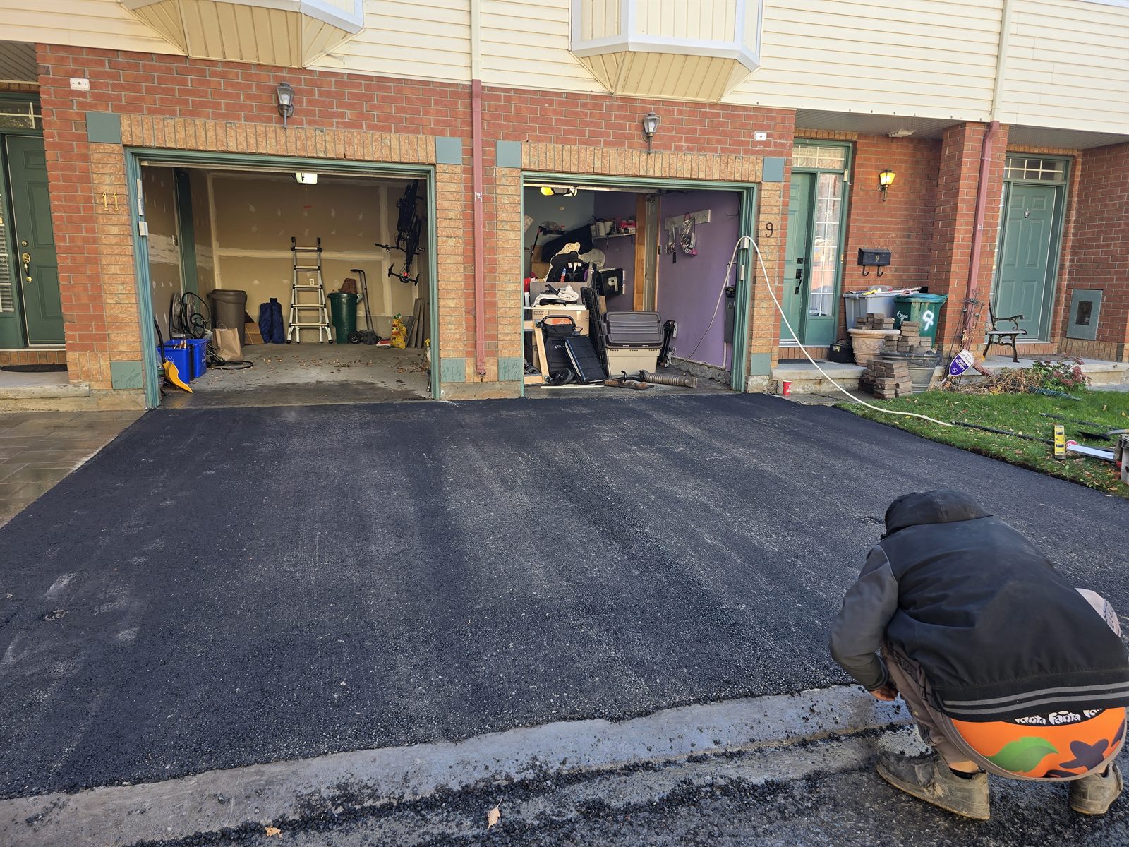 Freshly paved smooth black asphalt driveway between two garages in Ottawa