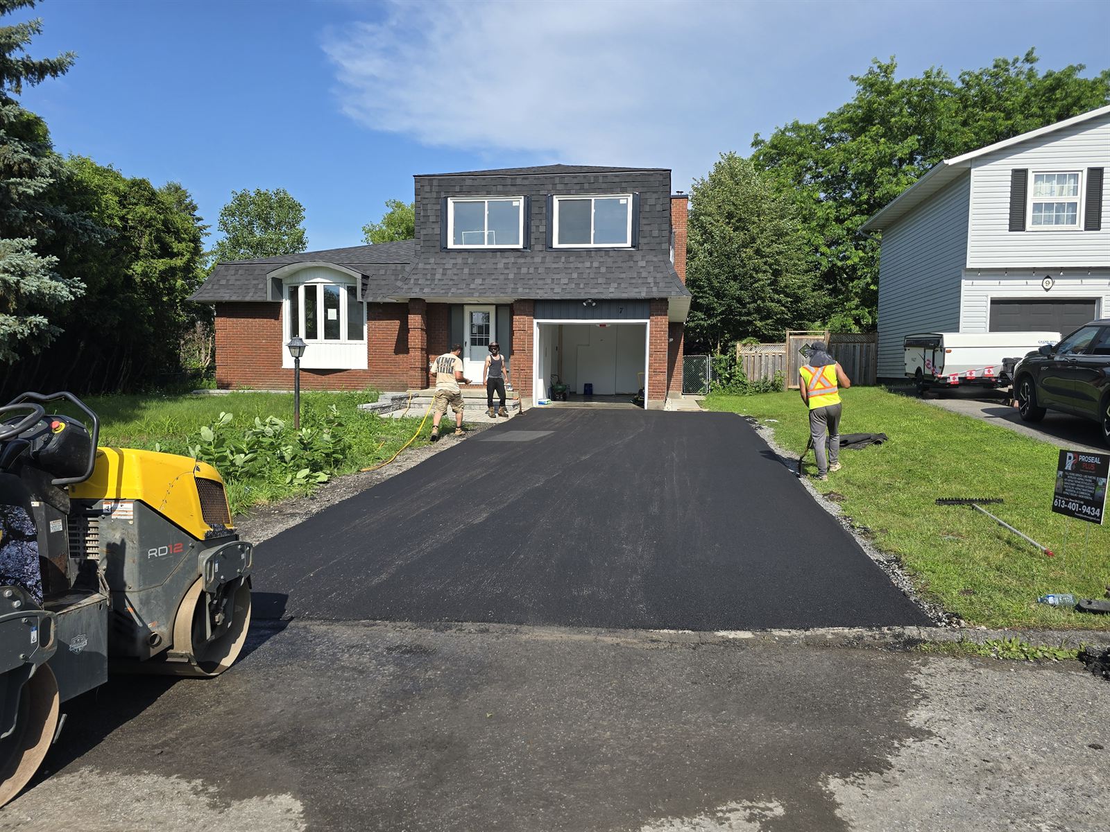 Proseal Plus Inc. crew paving and rolling a residential asphalt driveway in Ottawa
