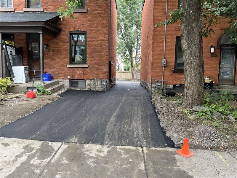 New asphalt driveway installed between two brick homes in Ottawa