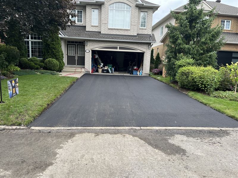 Freshly paved asphalt driveway at a two-storey brick home in Ottawa, Ontario