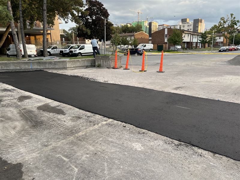 Fresh hot asphalt patch repair in a commercial parking lot in Ottawa