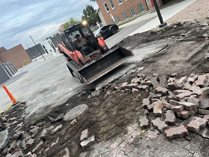 Track loader removing failed asphalt and pavers from a commercial lot in Ottawa