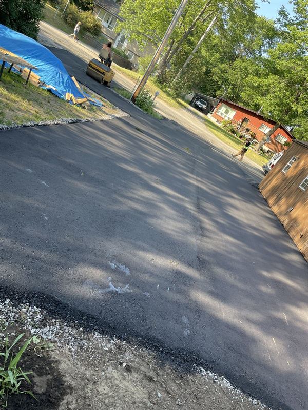 Ride-on roller compacting fresh asphalt on a residential driveway in Ottawa