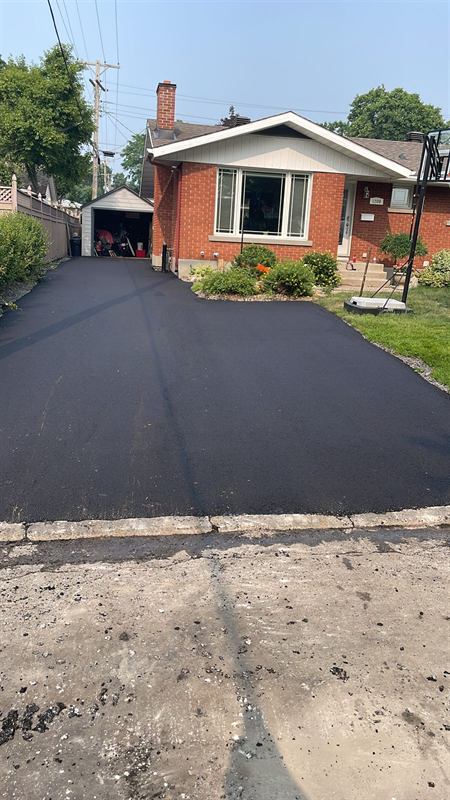 Freshly paved asphalt driveway leading to a brick bungalow in Ottawa
