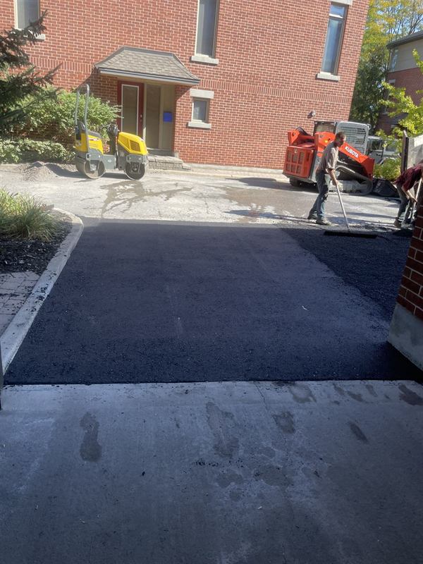 Freshly paved asphalt driveway with paving equipment still on site in Ottawa