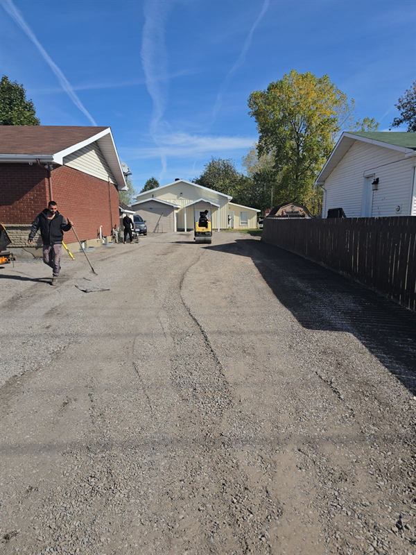 Paved laneway running between a fenced yard and a home in Ottawa