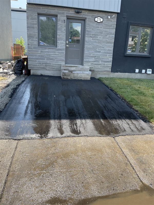 Sealed asphalt driveway cut in cleanly against concrete at a modern Ottawa home