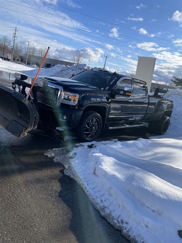Plow truck clearing snow from a commercial parking lot in Ottawa